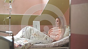 Young woman using laptop having video chat on hospital bed photo