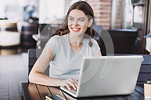 Young woman using laptop indoors. Beautiful happy girl working on computer in a cafe.
