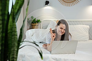 Young woman using laptop while lying on bed at home