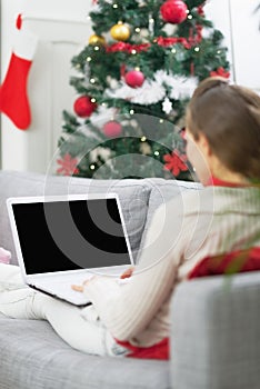 Mladá žena prenosný počítač najbližšie vianočný stromček . zadná 