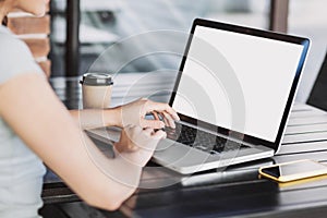 Young woman using laptop outdoor. Student girl working at a cafe. Blank white empty computer screen monitor.