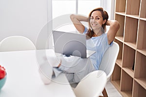 Young woman using laptop relaxed with hands on head at home