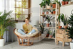 Young woman using laptop in room with home plants