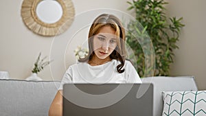 Young woman using laptop sitting on sofa at home