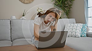 Young woman using laptop sitting on sofa at home