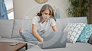 Young woman using laptop sitting on sofa at home
