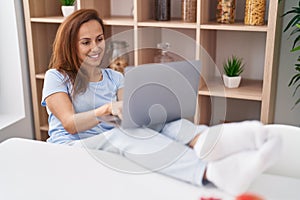 Young woman using laptop sitting on table at home