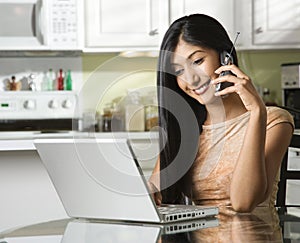 Young Woman Using Laptop and Talking on Cellphone