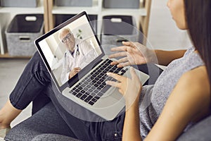 Young woman using laptop and talking to experienced senior doctor during online video consultation