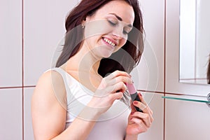 Young woman using mascara in bathroom