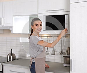 Young woman using microwave oven