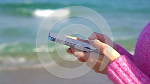 Young woman using mobile phone on the beach. Girl taking selfie by smartphone on the seashore