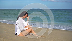 Young woman using mobile phone on the beach. Girl taking selfie by smartphone on the seashore