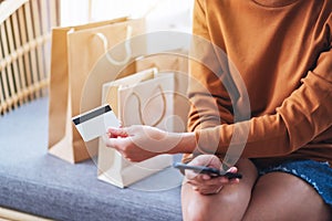 A young woman using mobile phone and credit card for online shopping