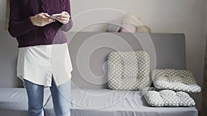 Young woman using mobile phone in home room. Girl typing message on smartphone