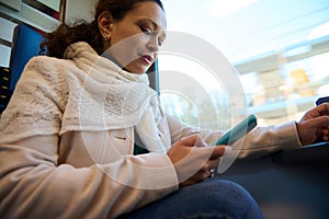 Young woman using mobile phone while travels by high speed train. Online communication. Internet. Rail road transport