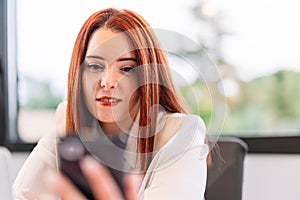 Young woman using mobile phone while working at home