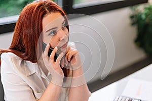 Young woman using mobile phone while working at home
