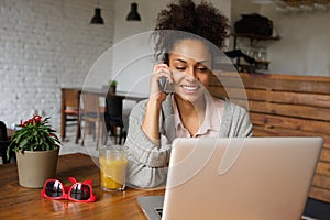 Young woman using mobile phone and working on laptop