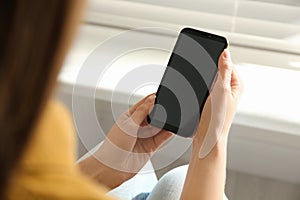 Young woman using modern smartphone indoors