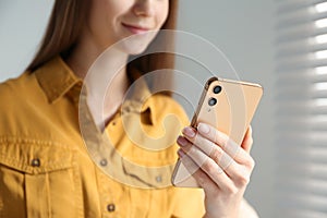 Young woman using modern smartphone indoors