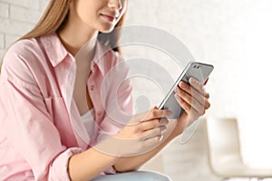 Young woman using modern smartphone indoors