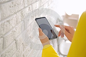 Young woman using modern smartphone indoors