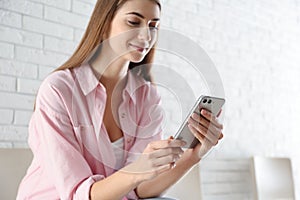 Young woman using modern smartphone indoors