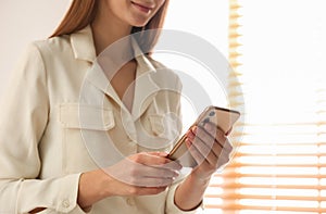 Young woman using modern smartphone indoors