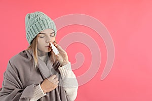 Young woman using nasal spray on pink background, runny nose concept