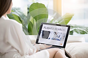 Young woman using online flight search tools on laptop