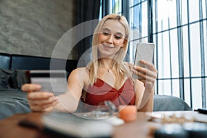 Young woman using online payment app via smartphone. Blithe