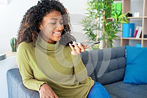 Young woman using phone vocal assistant at home