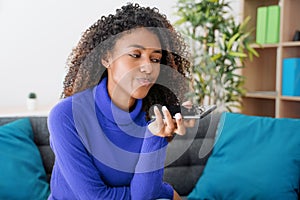 Young woman using phone vocal assistant at home
