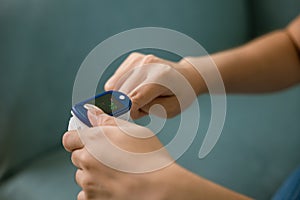 Young woman using pulse oximeter to monitor blood oxygen levels and pulse rate on finger