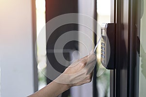 Young woman using RFID tag key card, fingerprint and access control to open the door in a office building