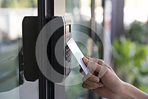 Young woman using RFID tag key, fingerprint and access control  to open the door in a office building