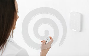 Young woman using security system indoors