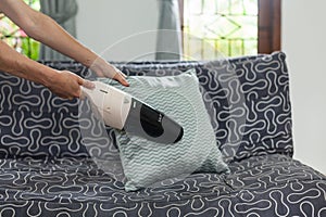 Young woman using a small manual vacuum cleaner while cleaning pillow on the couch