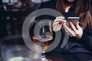 Young woman using smart phone at bar
