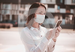 Young woman using smart phone in the city wearing face mask  and gloves protection for virus coronavirus covid 19