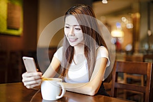 Young woman using smart phone in coffee shop