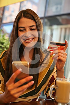 Young woman using smart phone and credit card.