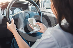 Young woman using smart phone while driving a car