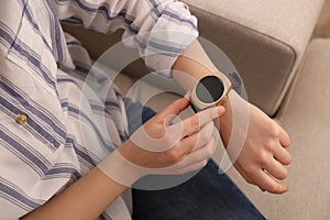 Young woman using smart watch at home, closeup view