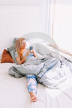 Young woman using smartphone in bed