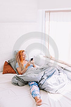 Young woman using smartphone in bed