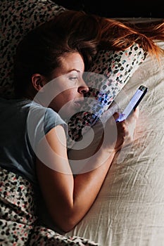 Young woman using smartphone in bed