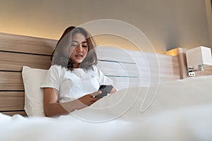 Young woman using smartphone on bed