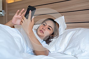 Young woman using smartphone on bed